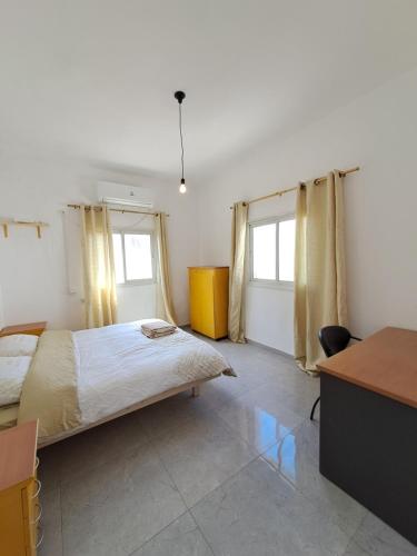 a bedroom with a large bed and two windows at Fellini talpiot roof dolce vita in Haifa