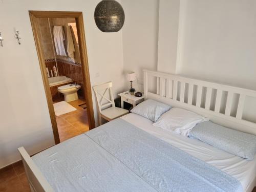 a bedroom with a white bed and a bathroom at Pinares de Lepe in Huelva