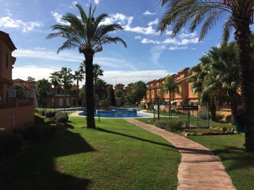 un complejo con piscina y palmeras en Pinares de Lepe, en Huelva