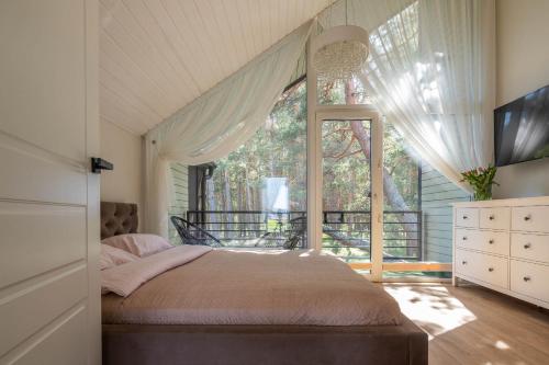 a bedroom with a bed and a large window at Forest Cottage in Palanga