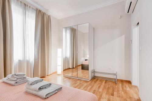 um quarto branco com uma cama e um espelho em Modern 2-bedroom apt, 200m from the Acropolis em Atenas