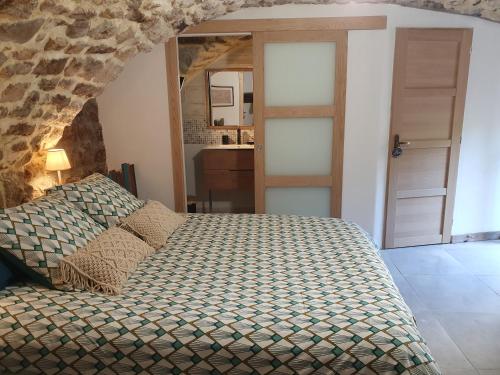 a bedroom with a bed and a stone wall at Chambres d'hôtes La Storya in Meyras