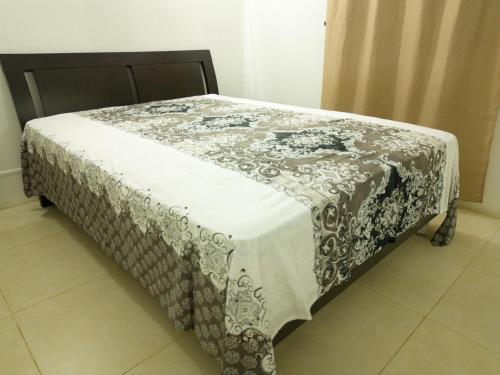 a bed with a black and white blanket on it at Le Paradisier Guest House in Rodrigues Island