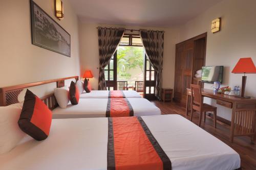 a hotel room with three beds and a desk at Windbell Villa Hoi An in Hoi An