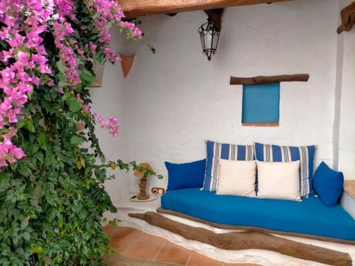 un sofá azul en un patio con flores rosas en Albaga, en Sant Jordi