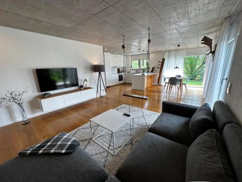 un salon avec un canapé noir et une cuisine dans l'établissement Moderne Ferienwohnung Rhenum mit Wallbox, à Waldshut-Tiengen