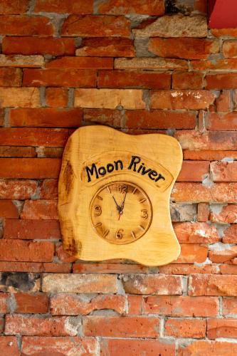 a wooden clock on a brick wall with the word moon river at Apartments MoonRiver in Bihać