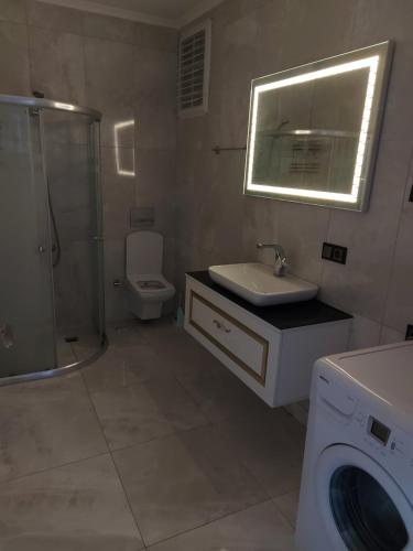 a bathroom with a sink and a washing machine at ÇOLAK SUIT in Arsin