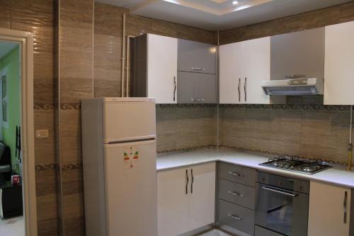 Una cocina con gabinetes blancos y un refrigerador. en LE JASMIN RESIDENCE bord de mer, en Hammam Sousse