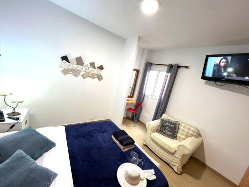 1 dormitorio con 1 cama y TV en la pared en ALCAMAR Habitaciones con baño compartido en apartamentos rurales cerca al Mar!, en Alcalá