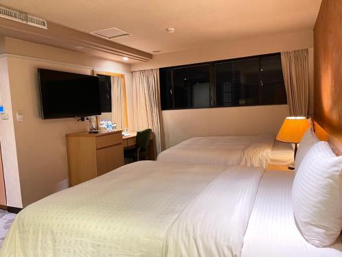 Habitación de hotel con 2 camas y TV de pantalla plana. en Dahshin Hotel en Taipéi