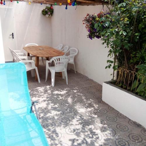 d'une terrasse avec une table en bois et des chaises blanches. dans l'établissement L'APPARTEMENT BOULONNAIS, à Boulogne-sur-Mer