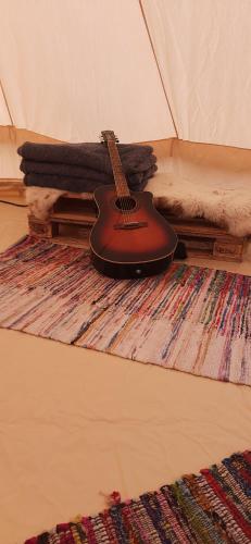 a guitar sitting on a rug in a tent at Campingul Apusenilor in Şuncuiuş