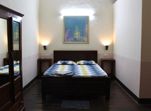 a bedroom with a bed and two lights on the wall at Royal Phoenix Inn in Panaji
