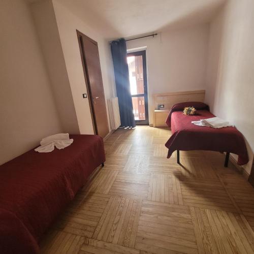 a room with two beds and a wooden floor at Chalet Monte Nebius in Vinadio