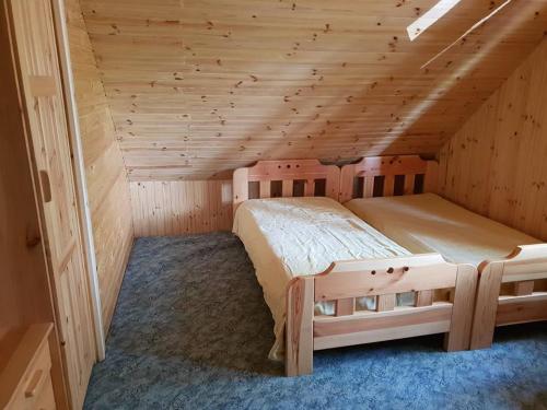 a bedroom with two beds in a wooden room at Dom nad Jeziorem Wigry Suwalszczyzna in Gawrych Ruda