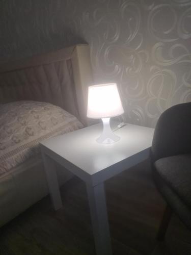 uma lâmpada sobre uma mesa ao lado de uma cama em Квартира у метро Спортивная em Kharkov
