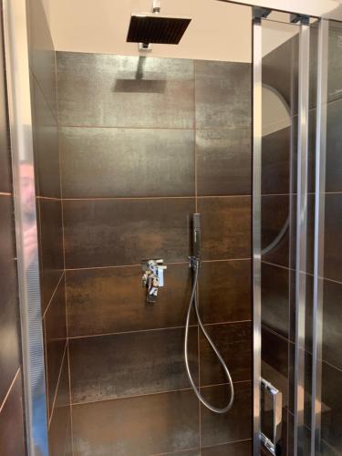 La salle de bains est pourvue d'une douche avec une porte en verre. dans l'établissement Harmony Navigli Apartment, à Milan