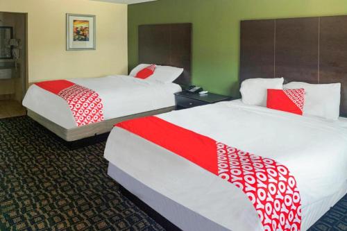 a hotel room with two beds with red and white sheets at OYO Hotel Rosenberg TX I-69 in Rosenberg