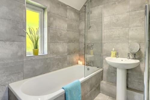 ein Badezimmer mit einer Badewanne, einem Waschbecken und einem Spiegel in der Unterkunft Park View - sleeps 7 great for 5 contractors in Warrington