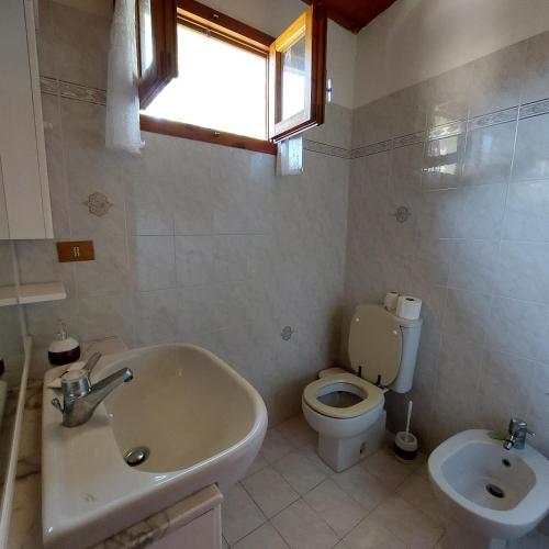 uma casa de banho com um lavatório, um WC e uma janela. em Appartamento a due passi dal mare a Quercianella em Quercianella