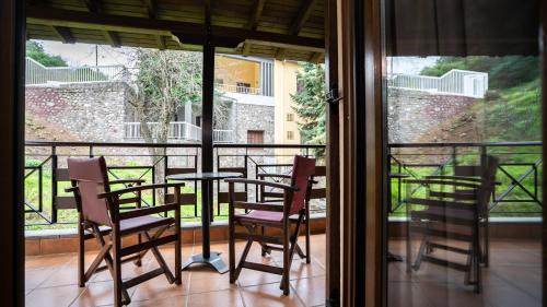 a balcony with a table and chairs and a window at Dellas Boutique Hotel in Kalabaka
