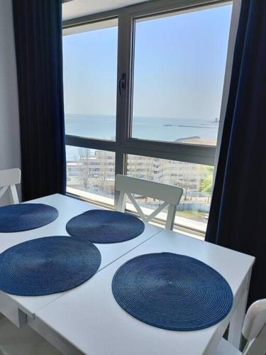 a white table with blue plates on it with a window at Olimp sea view in Olimp