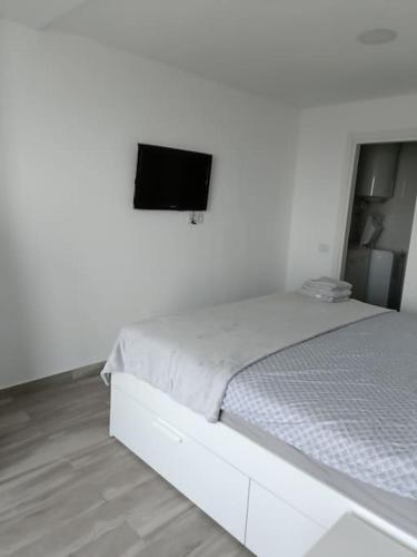 a white bedroom with a bed and a television at Olimp sea view in Olimp