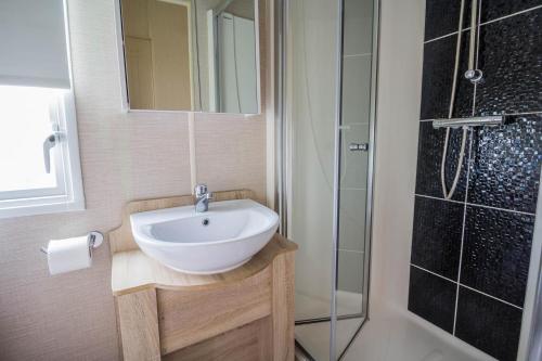 La salle de bains est pourvue d'un lavabo et d'une douche. dans l'établissement 8 Berth Caravan For Hire Near Clacton-on-sea In Essex Ref 26287e, à Clacton-on-Sea
