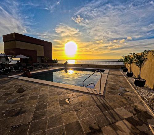 a swimming pool with the sunset in the background at Sol Vicitoria Marina in Salvador