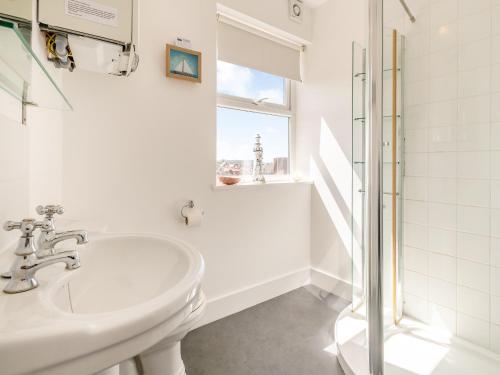 ein weißes Bad mit einem Waschbecken und einer Dusche in der Unterkunft Sea Wrack in Sheringham