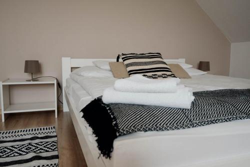 a white bed with black and white towels on it at Gospodarstwo agroturystyczne Pod Wielkim Wozem in Jerutki