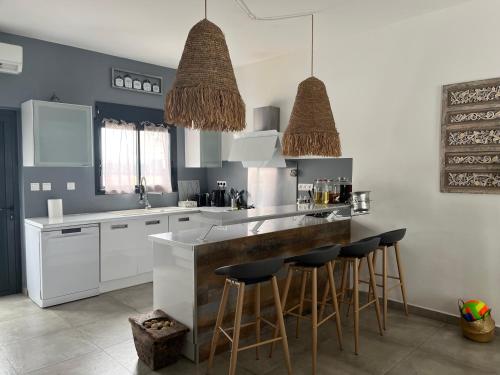 a kitchen with white cabinets and bar stools at Villa Ananas La Réunion et piscine chauffée in Saint-Denis