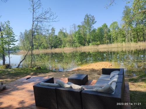 a couch sitting on a patio next to a lake at Pelakys Glamping Lounge in Šlepečiai