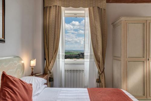 a bedroom with a bed and a window with a view at Hotel Palazzo di Valli in Siena