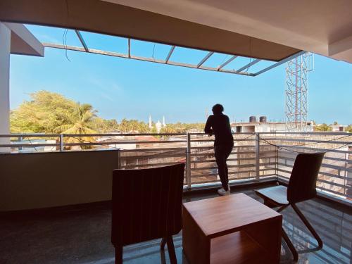 una persona parada en un balcón con vistas a la ciudad en Luxe Inn, en Kannur