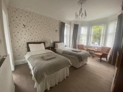 una camera d'albergo con due letti e una sedia di Lomond Guest House a Leven-Fife