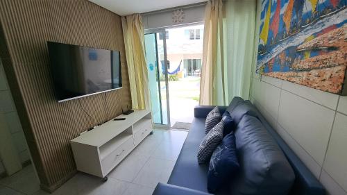 sala de estar con sofá azul y TV de pantalla plana en Casa de Luxo, 1 quadra do Mar em Porto de Galinhas, en Porto de Galinhas