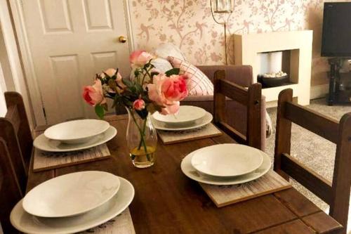 a dining room table with plates and flowers on it at Clock Tower Flats Morpeth in Morpeth