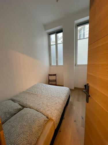 une petite chambre avec un lit et deux fenêtres dans l'établissement Appartement paris 16 eme, à Paris