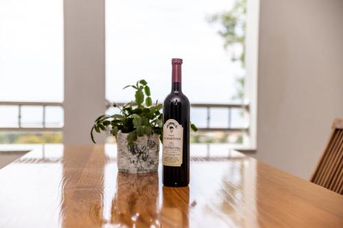 a bottle of wine sitting on a table with a plant at Apartmani Pero Dido in Rab