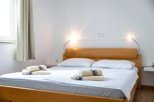 a bedroom with a large bed with two pillows on it at Apartmani Pero Dido in Rab