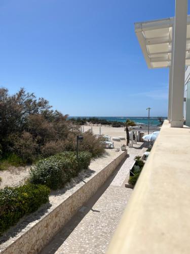 a walkway next to a beach with a building at Tabù Hotel in Porto Cesareo