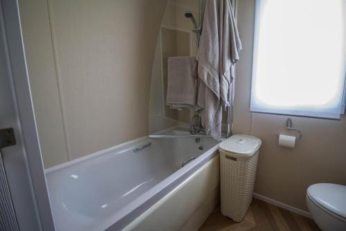 a bathroom with a tub and a toilet and a window at Beautiful Caravan At Highfield Grange Holiday Park In Essex Ref 26687p in Clacton-on-Sea