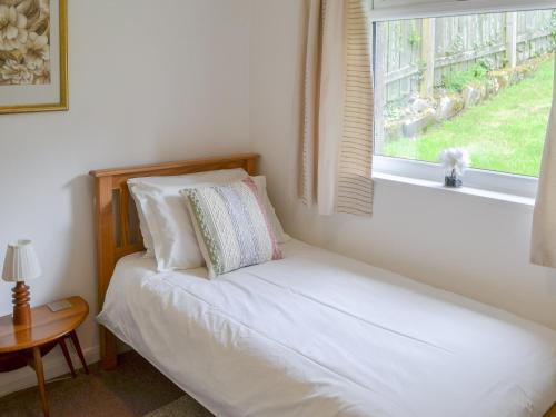 um pequeno quarto com uma cama e uma janela em Cairn Rigg em Rothbury