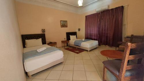 a bedroom with two beds and a table and a chair at Kasbat Aferdou in Er Rachidia