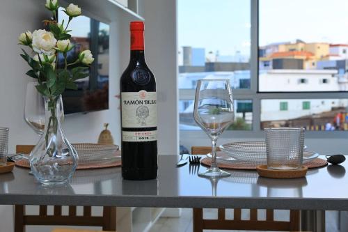 Una botella de vino sobre una mesa con dos copas. en Las Palmeras in Playa La Garita - beach apartment, en La Garita