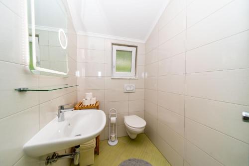 a white bathroom with a sink and a toilet at Apartmani Pero Dido in Rab