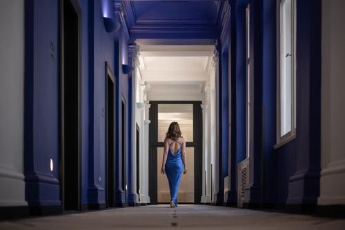 a woman in a blue dress walking down a hallway at Century Old Town Prague - MGallery Collection in Prague