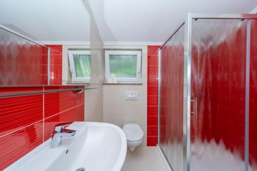 a red bathroom with a sink and a shower at Apartmani Pero Dido in Rab